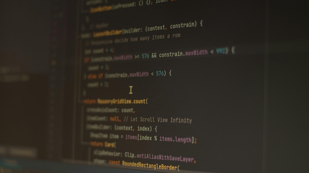 Developer debugging code on multiple monitors to represent technical cybersecurity challenges
