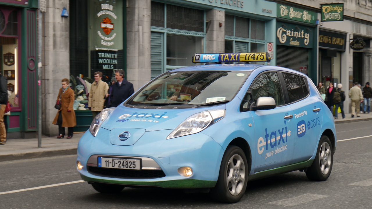 Person charging an electric car in a driveway illustrating lower fueling costs