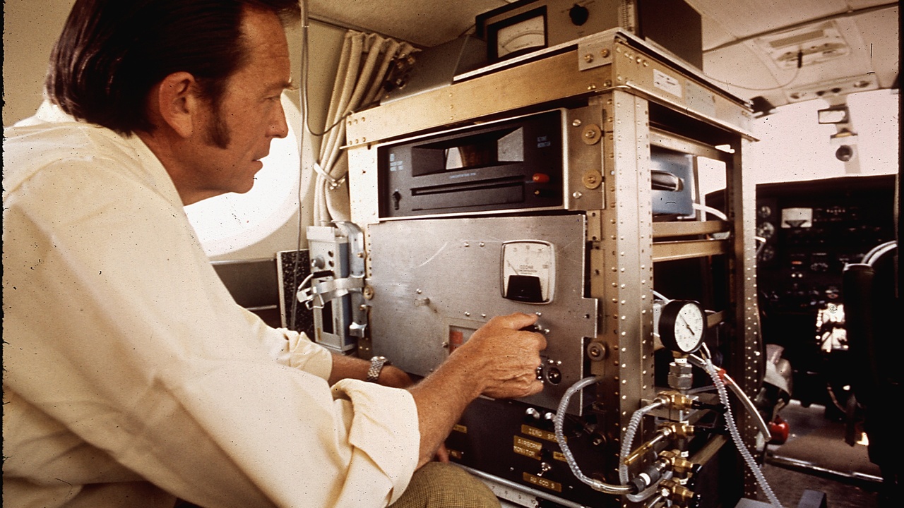Field researchers using portable water-quality sondes and soil corers at a riverbank