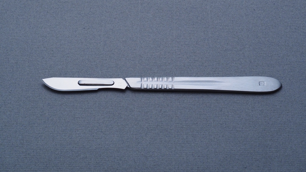 Scalpel and surgical scissors on sterile drape.