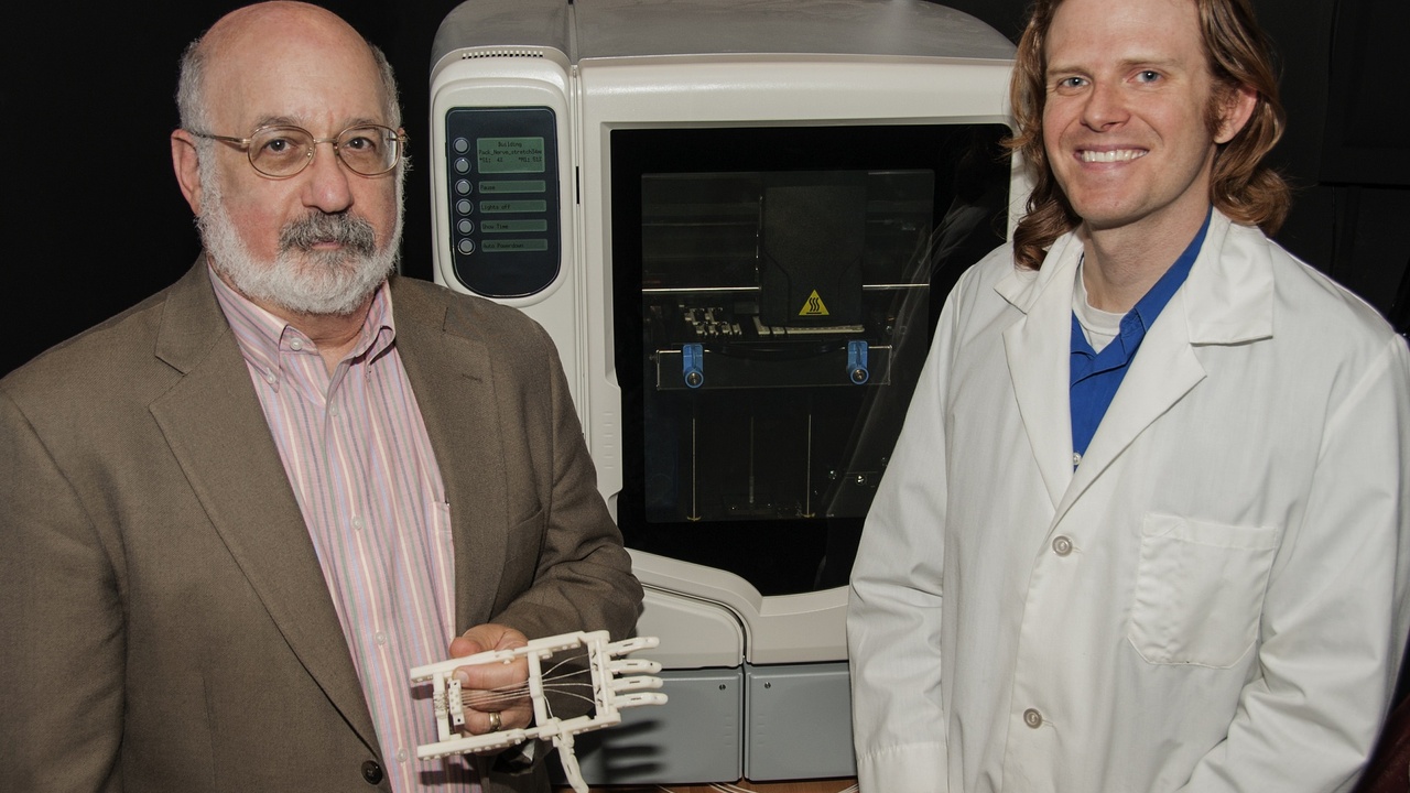 Engineer working on CAD model of a medical device next to a desktop 3D printer.