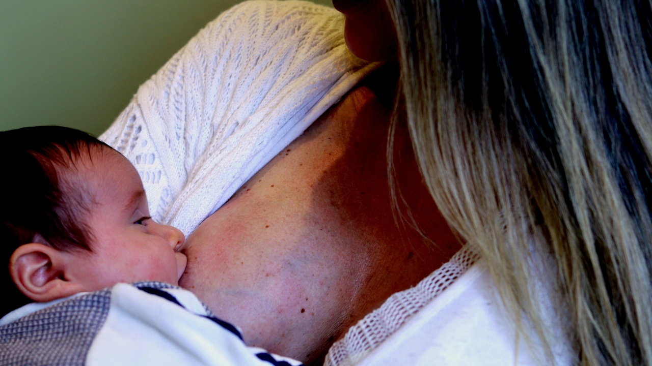 Newborn being breastfed showing colostrum and early skin-to-skin contact