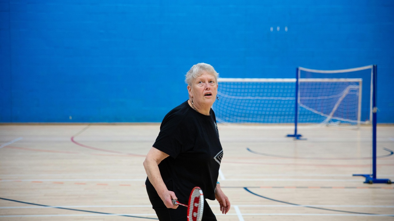Two older adults walking briskly in a park, representing healthy aging