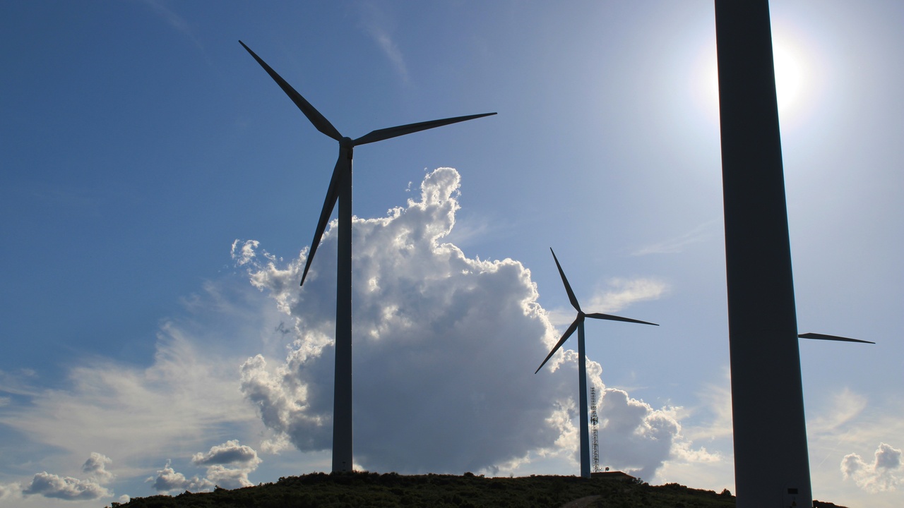 Solar panels and wind turbines near a city skyline representing clean energy solutions.