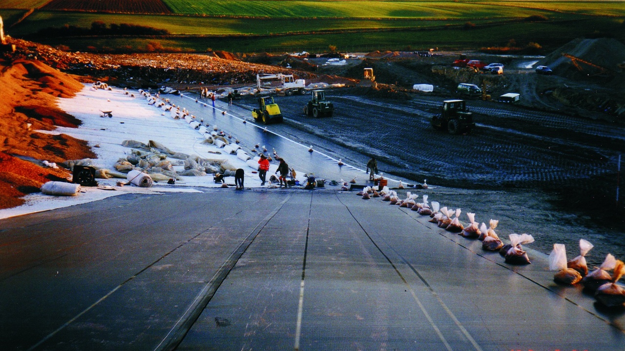 Cross-section diagram of a sanitary landfill showing liners, leachate pipes, and gas wells