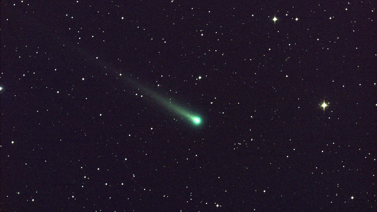 Comet with bright coma and long tails visible against starry sky