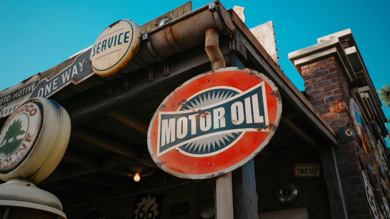 Mechanic checking car oil next to battery and maintenance checklist