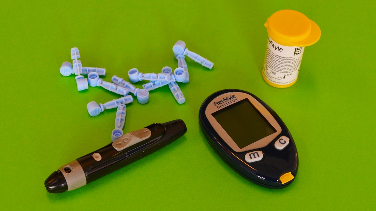 Hands holding prescription insulin vials with price tags and digital diabetes tools in background