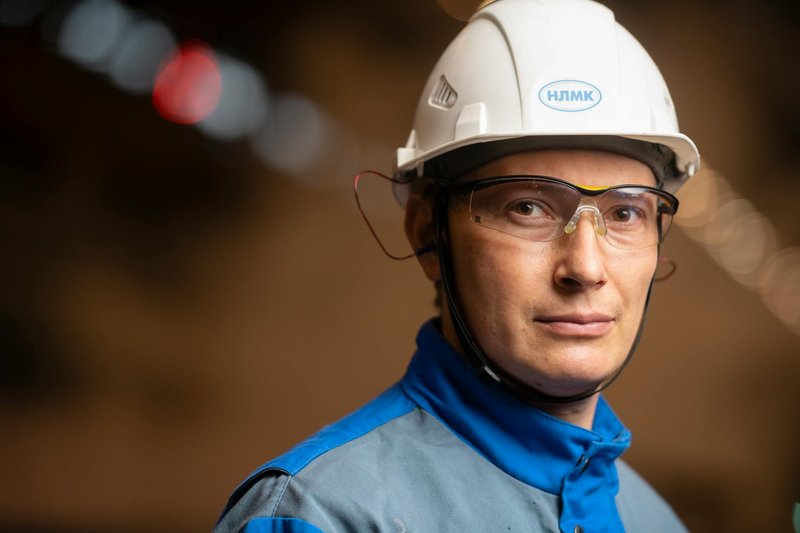Confident male engineer wearing safety helmet and goggles in industrial setting.