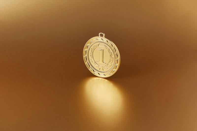 Close-up image of a golden number one medal on a soft golden background.