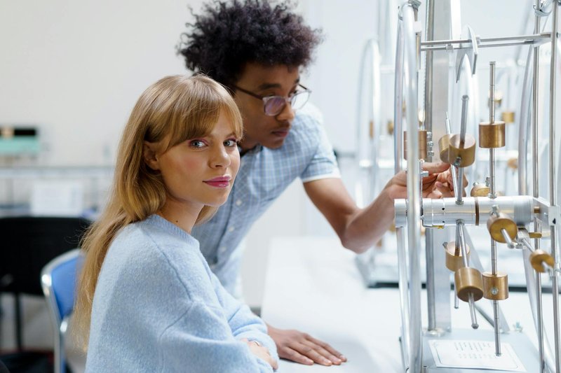 University students exploring physics concepts in a laboratory setting with experimental equipment.