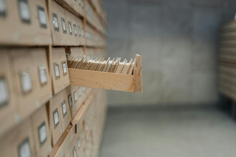 A vintage card catalog drawer in an archive library setting, highlighting organization and history.