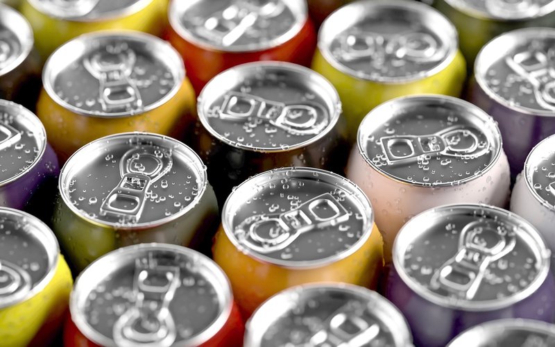 Close-up of colorful beverage cans with condensation droplets on the pull tabs.