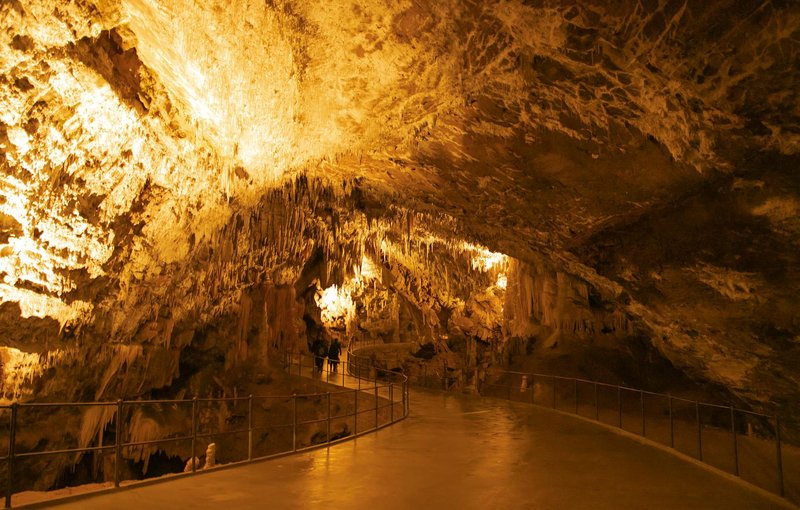 Explore the stunning formations of Postojna Cave in Slovenia, showcasing dramatic stalactites and lighting.