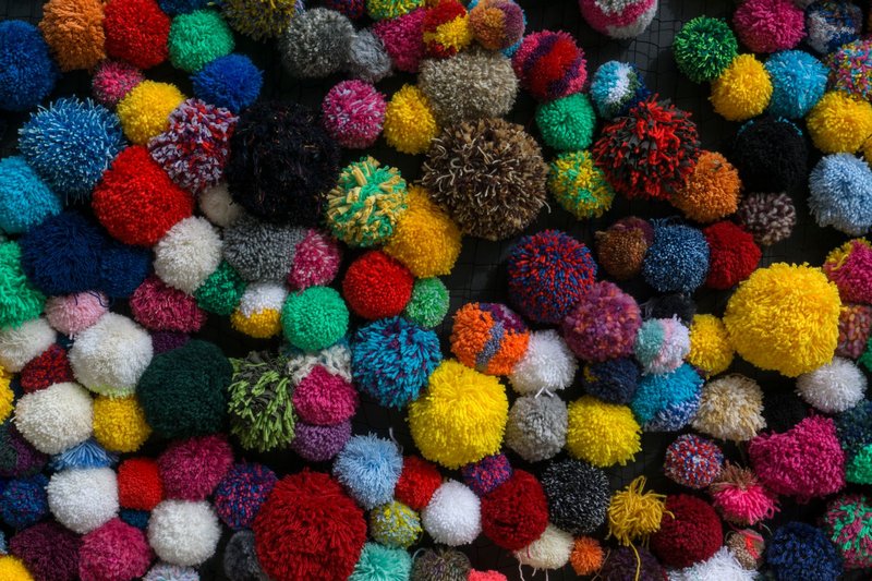 A vibrant collection of handmade yarn pom poms displaying a variety of colors and textures.