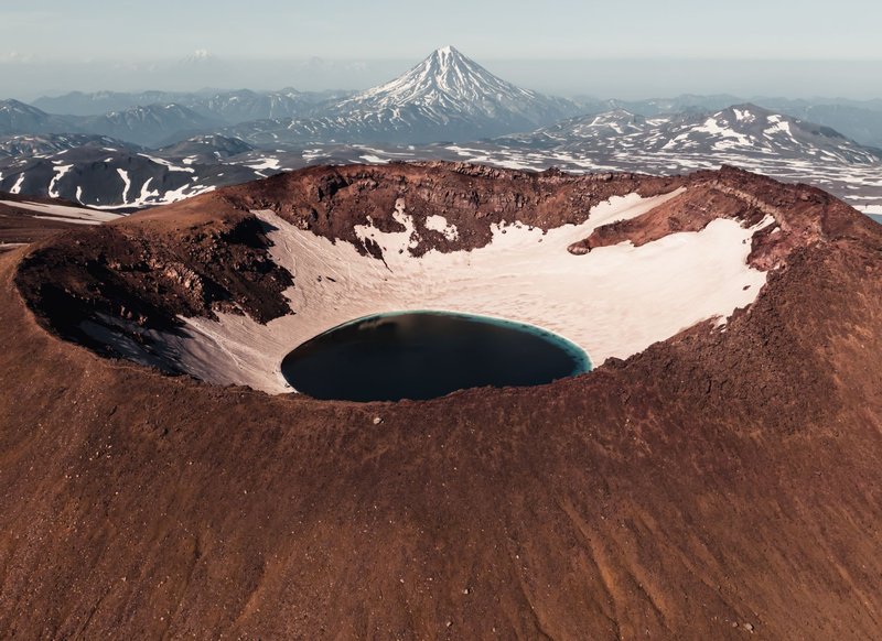 Stunning aerial view of a volcanic crater with a lake in Kamchatka, Russia, showcasing natural beauty and geological formations.