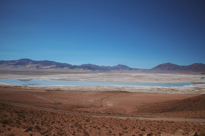 A breathtaking view of salt flats and desert with mountains under a clear blue sky.