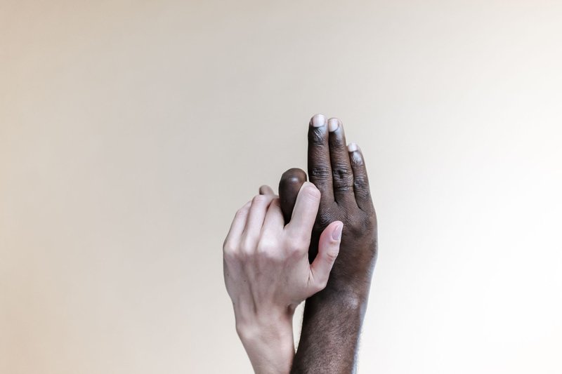Close-up of two diverse hands touching, symbolizing unity and support.