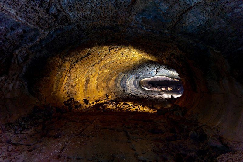 Explore the serene depths of this naturally formed cave tunnel, illuminated with warm tones.
