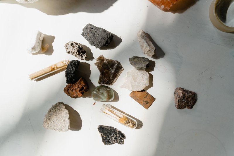 Various minerals and rocks arranged on a sunlit table, showcasing natural textures and colors.