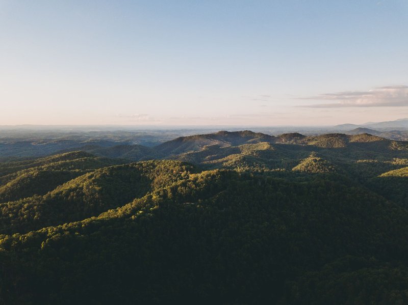 Breathtaking aerial panorama of green mountain ranges under a clear sky.