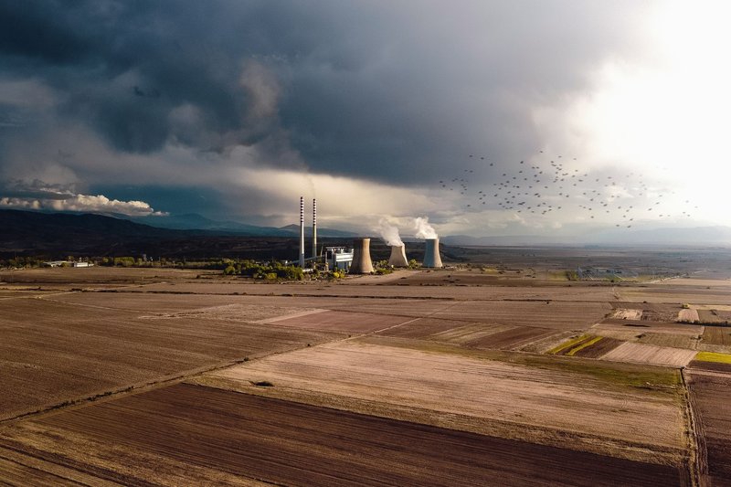 Aerial view of empty fields near atomic power station generating energy and polluting atmosphere