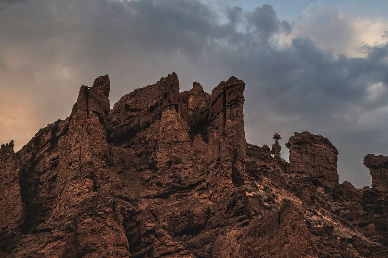 Majestic rock formations under a moody, cloud-filled twilight sky.
