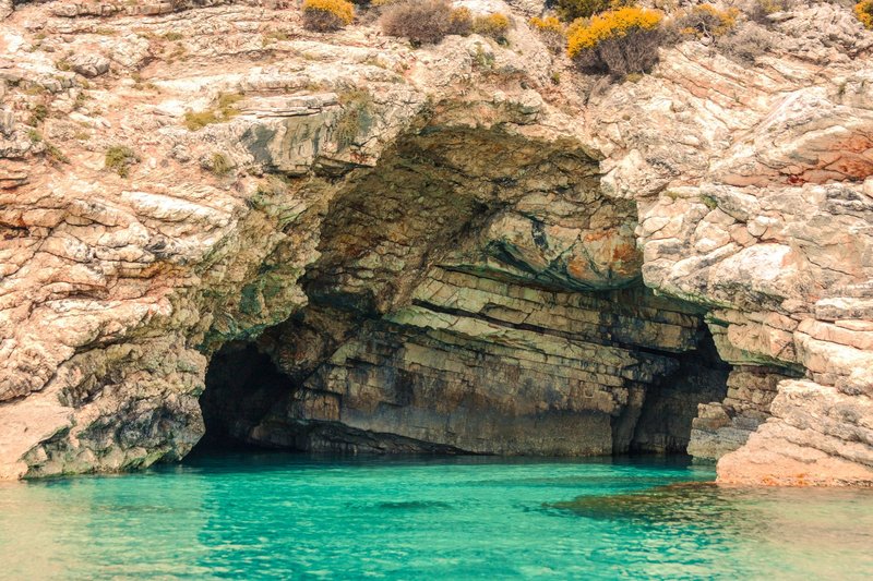 Explore a stunning sea cave in Greece with turquoise waters and rugged cliffs.