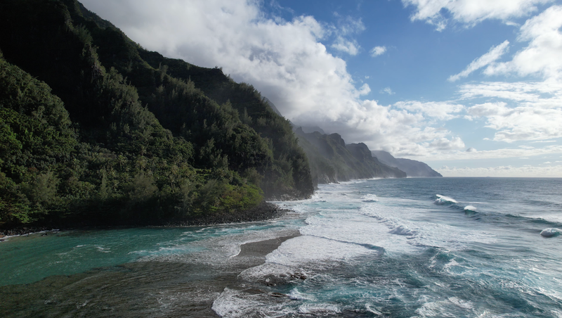 A breathtaking aerial view of Na Pali Coastline with lush cliffs and the Pacific Ocean.