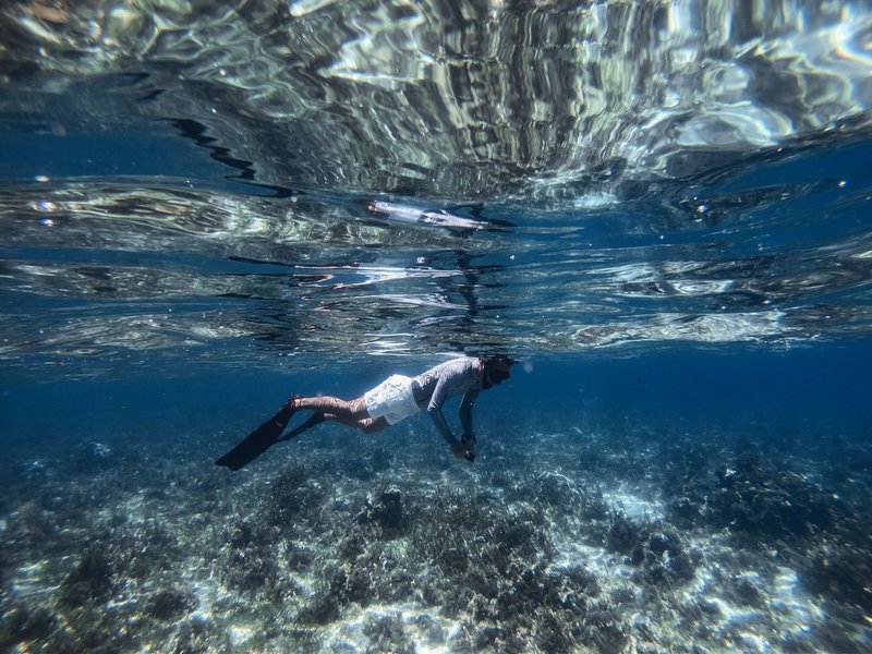 A snorkeler enjoys the clear blue water and coral reefs, capturing the essence of adventure and leisure.
