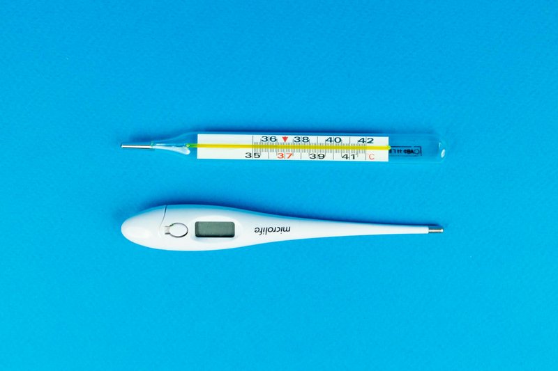 Digital and mercury thermometers on blue background for medical concept.
