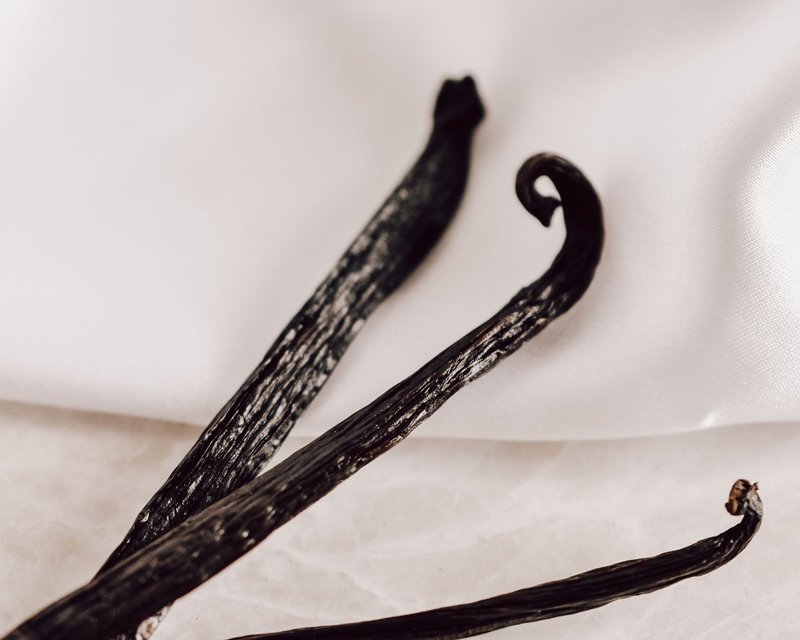 Detailed close-up of natural vanilla beans on a white background, perfect for culinary projects.