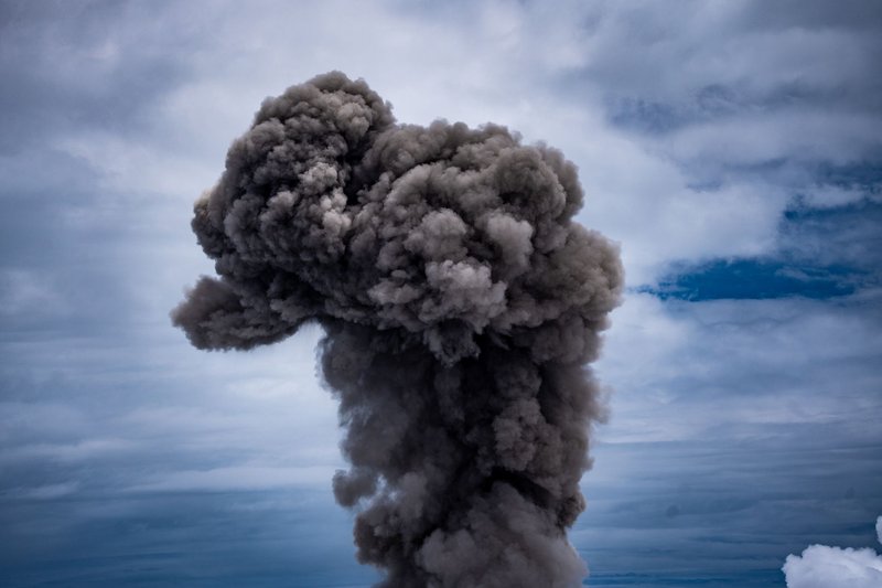 A spectacular display of volcanic ash rising into a cloudy sky, illustrating natural power.