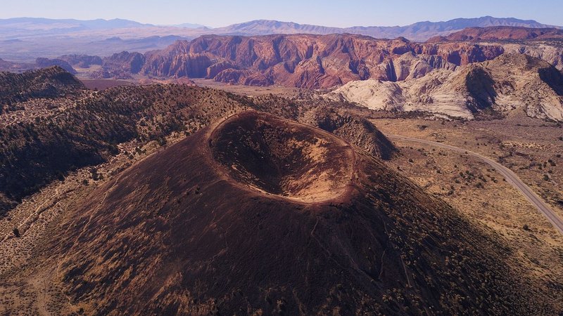 Stunning aerial shot of a dormant volcanic crater surrounded by desert terrain and mountains.