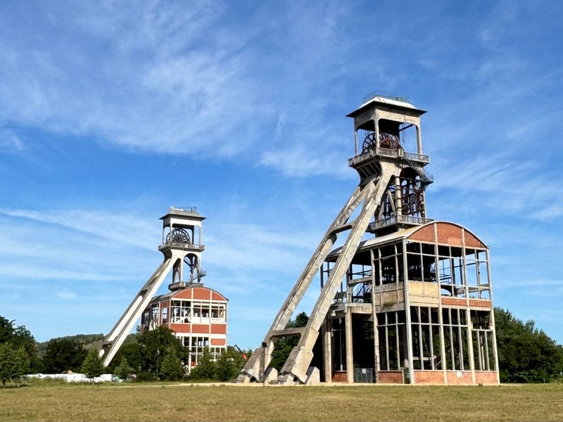 Two abandoned mine tower structures stand tall under a clear blue sky, highlighting industrial history.