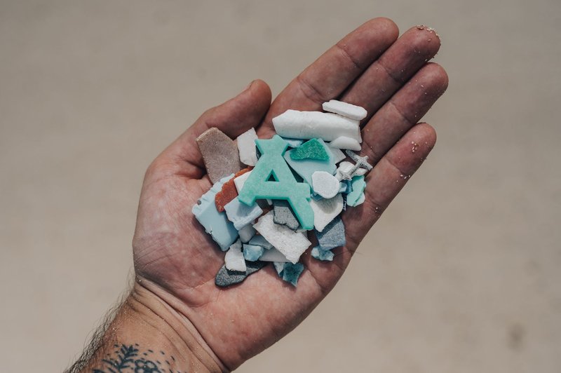Close-up of a hand holding colorful plastic fragments, highlighting environmental concerns.