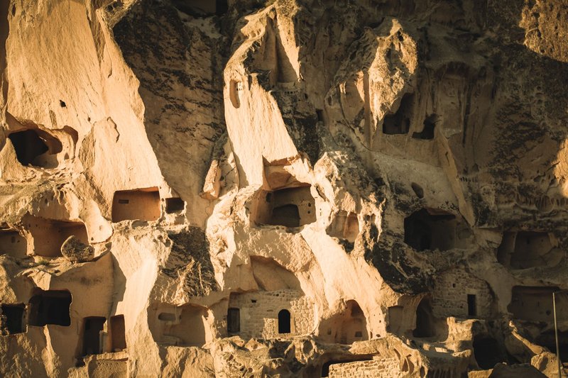 Explore the ancient cave dwellings carved into the rocks of Nevşehir, Turkey, bathed in sunlight.