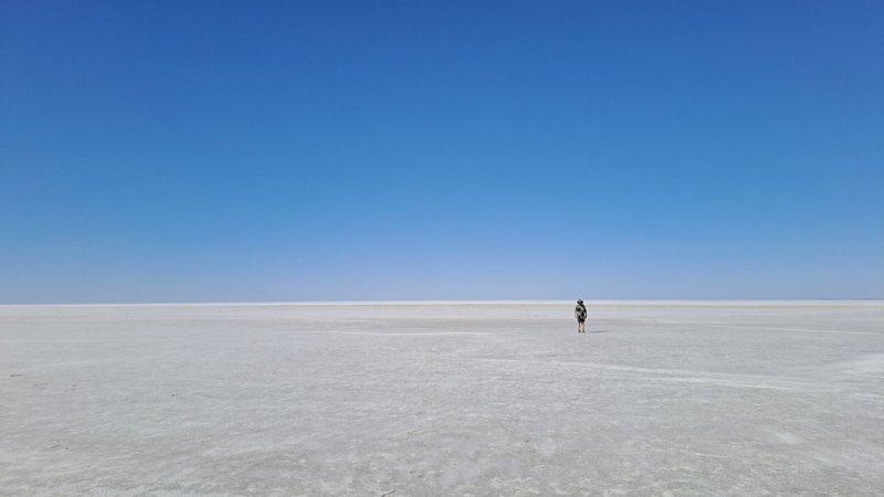 A lone traveler explores the expansive salt flats under a clear blue sky in South Australia.