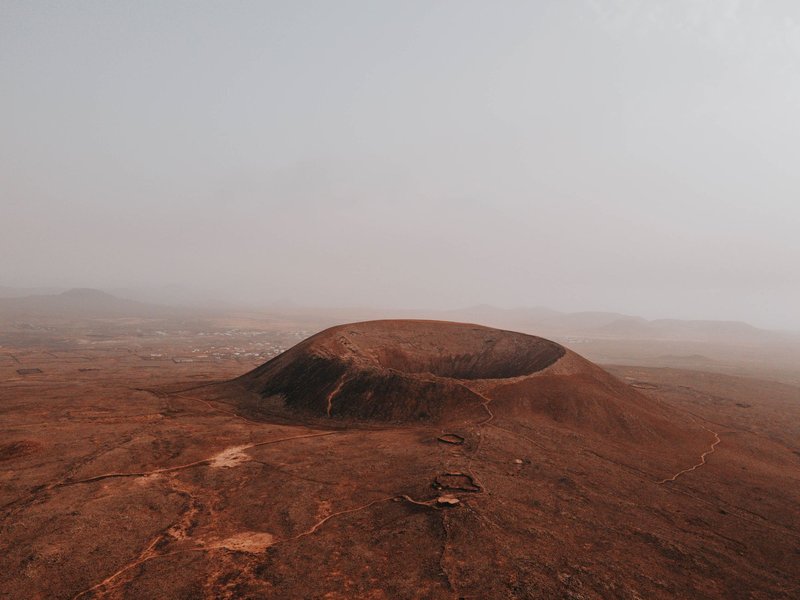 Stunning aerial view of Calderon Hondo volcano amidst a foggy, arid landscape in Spain.