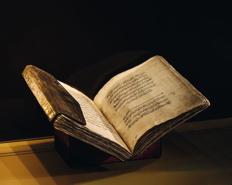 A vintage manuscript with Arabic script open to reveal beautifully aged pages, showcased elegantly.