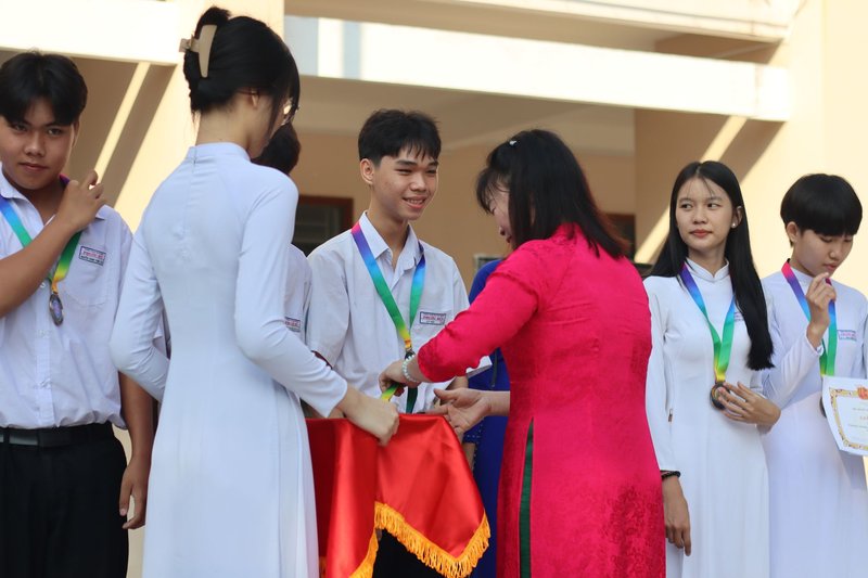 Students receiving medals and certificates during a school award ceremony.