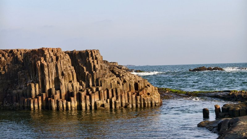 Captivating view of columnar basalt formations against a coastal backdrop, highlighting natural beauty.