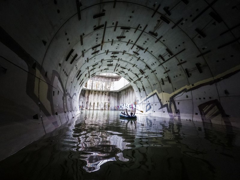 Canoeing through an eerie, graffiti-covered tunnel filled with water.