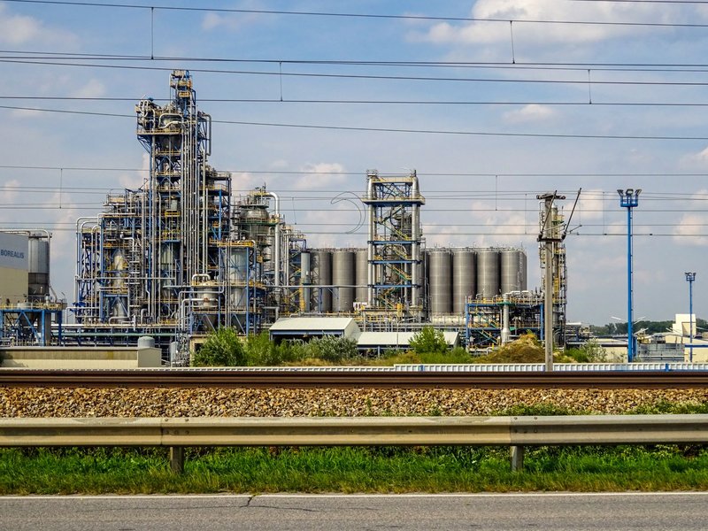 Image of a large chemical factory in Schwechat, Austria, showcasing industrial pipes and machinery.
