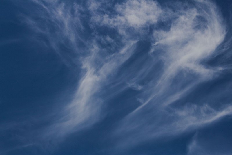 Capture of wispy cirrus clouds against a deep blue sky, symbolizing tranquil weather.