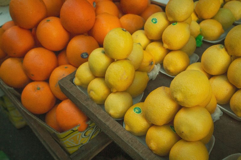 Vibrant display of fresh lemons and oranges at an outdoor market. Ideal for health and nutrition themes.