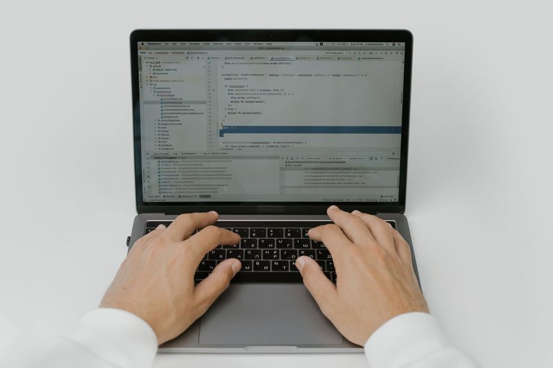 Close-up of hands coding on a laptop, showcasing software development in action.