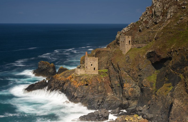 Explore the dramatic cliffs of Cornwall with historical tin mine ruins overlooking the ocean.