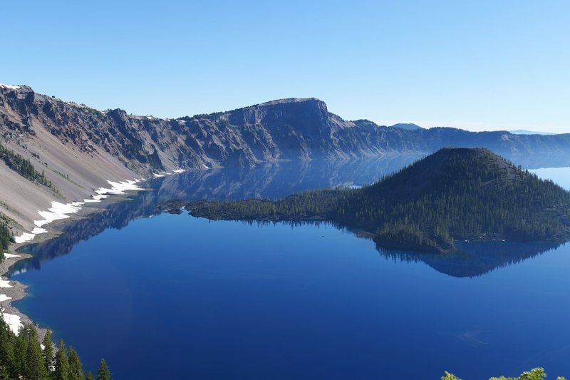 Aerial shot of Crater Lake National Park with clear blue water and surrounding cliffs.