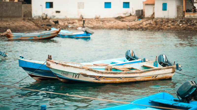 Small fishing boats in a calm harbor in Tadjoura, Djibouti with coastal buildings in the background.